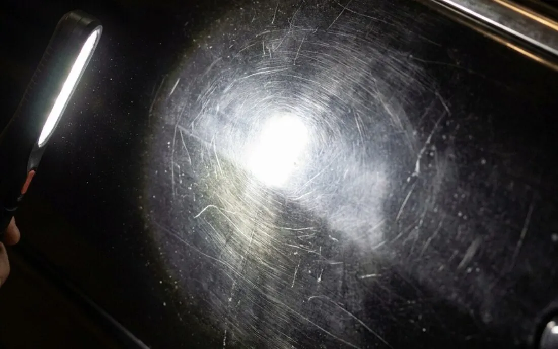 Car paint with heavy swirl marks and scratches visible under inspection light before correction